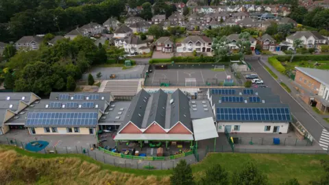 Getty Images Aerial view showing a school with a playground and two buildings covered in rooftop solar panels.