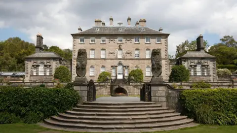 A large 18th century house, seen from the outside. It has large gardens around it.
