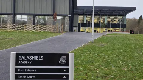 SBC A sign for Galashiels Academy in the foreground with a path leading up to a modern school building with a flat roof