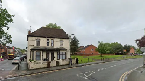 A two-storey cream building on the corner of two residential streets 