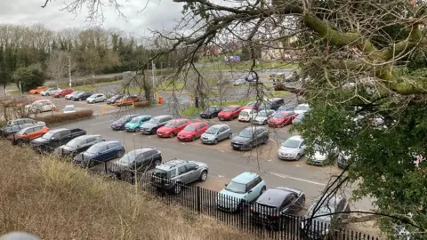 Martin Heath/BBC Car park seen from above. There is a tree in the foreground. There are cars parked in almost every space. There is a section to the right separated from the rest by a low height bar.