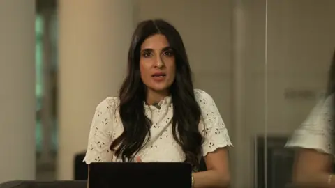 The BBC's Nomia Iqbal, in a cream top, addresses the camera