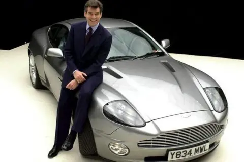 James Bond actor Pierce Brosnan with the Aston Martin Vanquish sold at auction