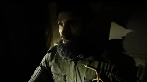 A photo of Abu Jarrah, his face lit alone in the dark. 