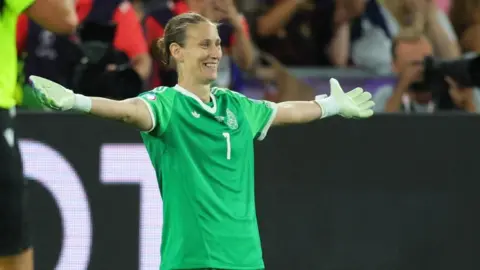 Ann-Katrin Berger in green spreads her arms in celebration