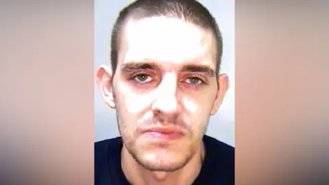 Humberside Police A police custody image of a man wearing a black t-shirt. He has a stubble beard and short dark hair and is staring expressionless into the camera.