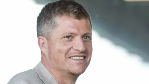 Southend United FC Justin Rees in a grey suit jacket, smiling