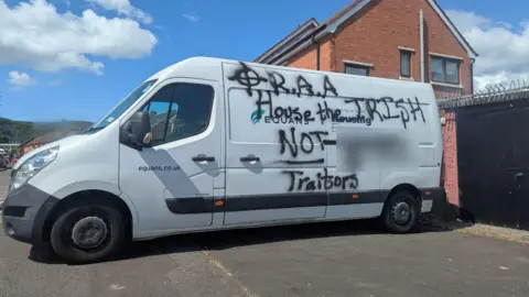 A white van with spray paint on it that says R.A.A House the Irish not (then a blurred out word) - traitors