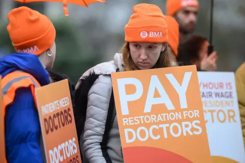 Getty Images Resident doctors hold placards reading 'pay restoration for doctors' as they strike in London in November.