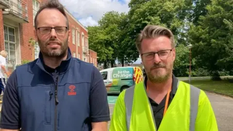 Aled Thomas / LDRS Two men, one wearing a blue body warmer, and the other wearing a yellow high visibility jacket stand in front of a Swindon Borough Council van. 
Rob Brown Head Of Waste Collection And Councillor Chris Watts
