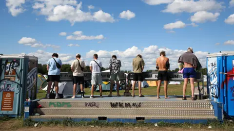 Men stand at urinals at a festival