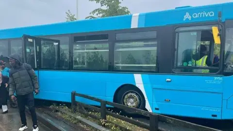 A bright blue bus partially mounted on a walkway.
