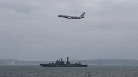 Royal Navy Image shows an RAF maritime patrol aircraft in the sky over a Russian warship