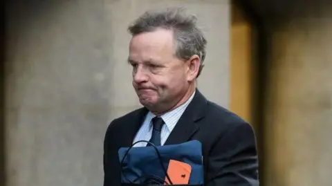 Close up image of Andy Hill in suit going in to High Court in London