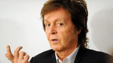 Headshot of musician Paul McCartney, wearing black blazer and open-necked shirt, taken in 2014 