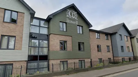 A large three-storey modern looking building with a gabled roof