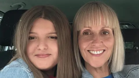 A mother and daughter pose for a selfie inside a car