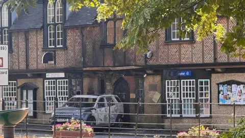 The burned out remains of a Land Rover Discovery Sport that was used to ram the Town Hall in Ivinghoe. Windows around the vehicle are damaged. 