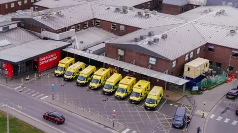 An arial picture of East Surrey Hospital's A&E department with eight ambulances lined up outside the main entrance.
