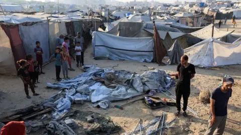 Reuters Palestinians inspect damage at the site of an overnight Israeli strike on tents sheltering displaced people, in Gaza City (22 July 2025)