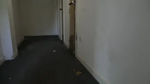 The footage shows an empty corridor in one of the blocks, with rubbish strewn across the floor.