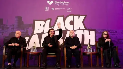 Birmingham City University Four people, including Ozzy Osbourne on the far right, are sitting down in front of a background showing the Birmingham skyline in purple and with the words Black Sabbath. 