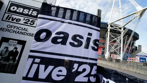 Large Oasis logos saying "Oasis Live 25" with the Cardiff Principality Stadium in the background