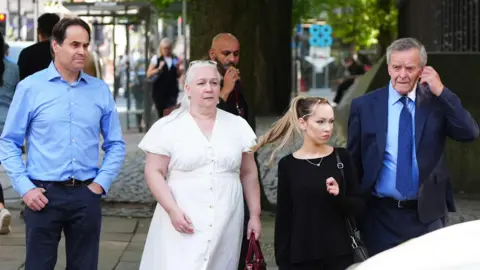 PA Media Paula Leeson's brother Neville Leeson (left) and father Willy Leeson (right) outside Manchester Civil Justice Centre
