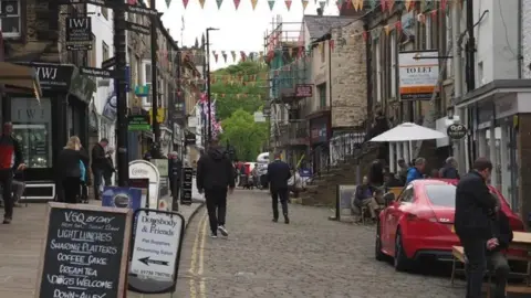 Tom Airey/BBC A picture of Skipton's high street with people milling around outside shops and cafes