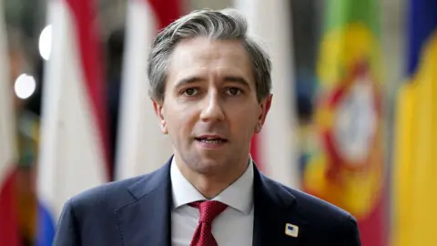 Getty Images Simon Harris looking at the camera, wearing a white shirt, red tie and navy blazer.