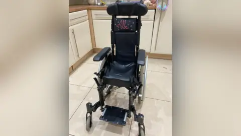 A child's wheelchair with the name Alba on the seat back