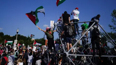 EPA A group of protesters waving Palestinian flags climb a structure