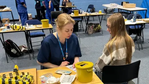 A student about to receive the Meningitis B vaccine at the University of Kent sports hall