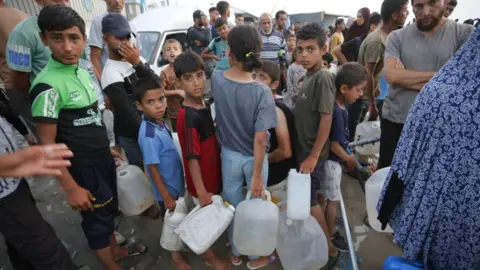 Displaced Palestinians queue for water in Deir al-Balah, central Gaza (22 May 2024)