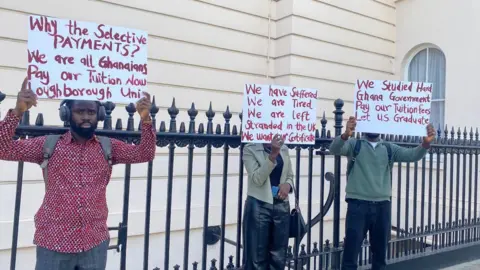 Supplied Three Ghanian students holding up placards calling for their university fees to be paid