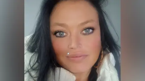 A woman with long dark hair wearing a white puffer jacket.