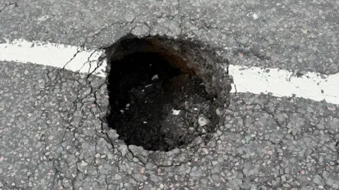 Jewel Miah A sinkhole in a tarmac road surface