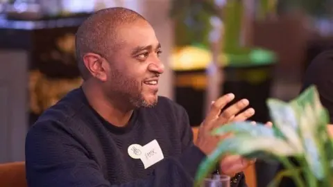 Peter Reeves A man wearing a black jumper smiling while talking