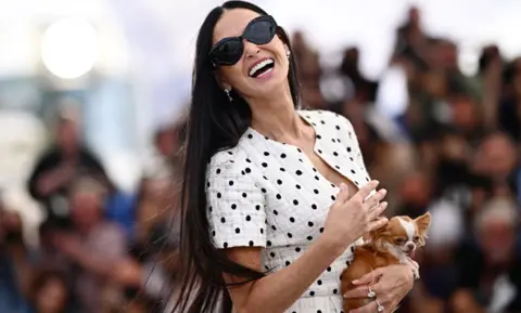 Getty Images A atriz americana Demi Moore segura seu cachorro Chihuahua chamado Pilaf enquanto posa durante uma sessão de fotos para o filme "A Substância" na 77ª edição do Festival de Cinema de Cannes em Cannes, sul da França, em 20 de maio de 2024