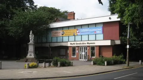 Jonathan Thacker/Geograph The outside of North Lincolnshire Museum with banners across the upstairs windows and a war memorial in the square outside