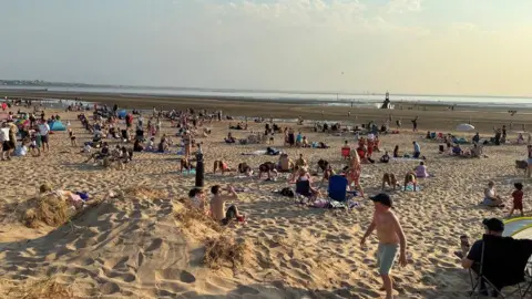 People scattered across Crosby beach view the eclipse.