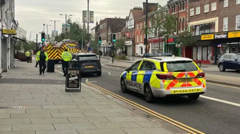 A police car and fire engine on High Street North in Dunstable, where a fire engine and a vehicle are stopped as officers speak to people at the scene.