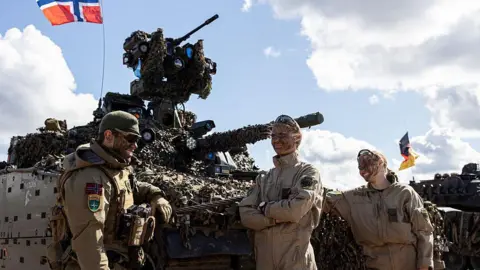 Getty Images Nato troops from Denmark and Norway stand in front of a tank during exercises in May 2025