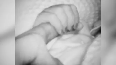 Kaeti Morrison A black and white photo of a baby hand holding a woman's finger 