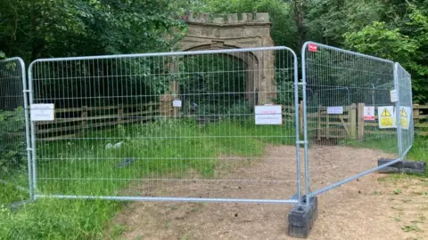 Martin Heath/BBC Stone arch gate surrounded by metal fencing