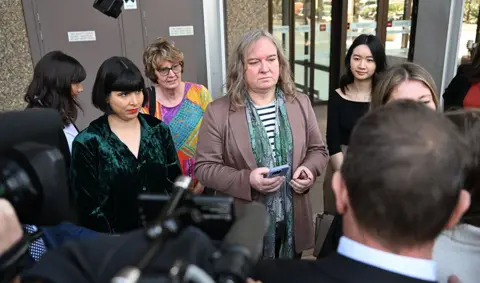 EPA Roxanne Tickle (centre) looks on as she is surrounded by people while speaking to press outside the Federal Court of Australia in Sydney on 23 August.