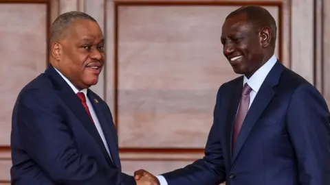 Kenya President William Ruto (R) and Haiti Prime Minister Garry Conille (L) shake hands after addressing a joint press conference during Conille's official state visit, at the Statehouse in Nairobi, Kenya, 11 October 2024