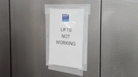 LDRS A sign with the BCP Council logo has been sellotaped to a lift door. It reads "lifts not working".