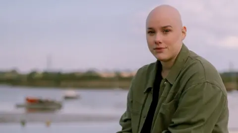 Isaac Qureshi Laura wearing a green jacket with a river in the background.