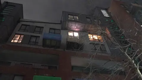 Pictured at ground level looking up, the image shows Canada Court at night. Some lights on in meaning are few windows are lit up.